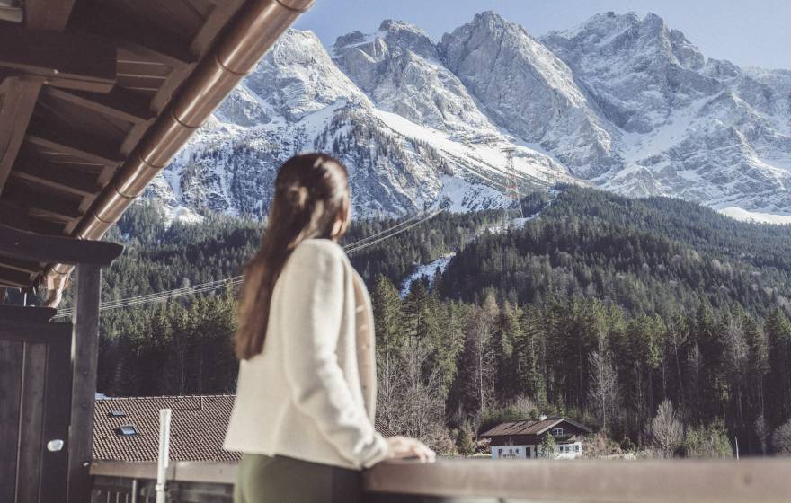 Frau steht auf Balkon mit Blick auf die Zugspitze